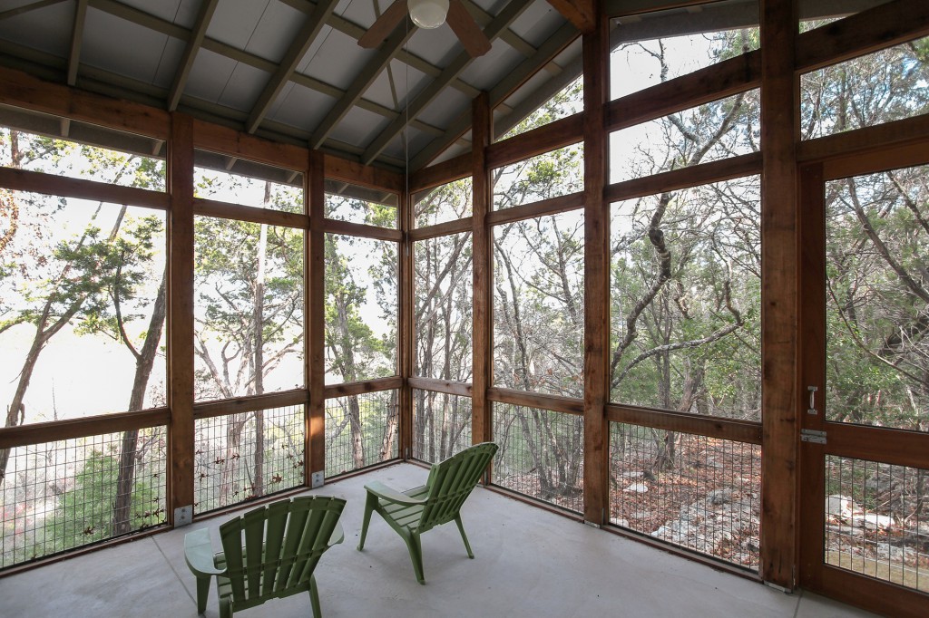 Screened porch off master bedroom overlooks hill country view.