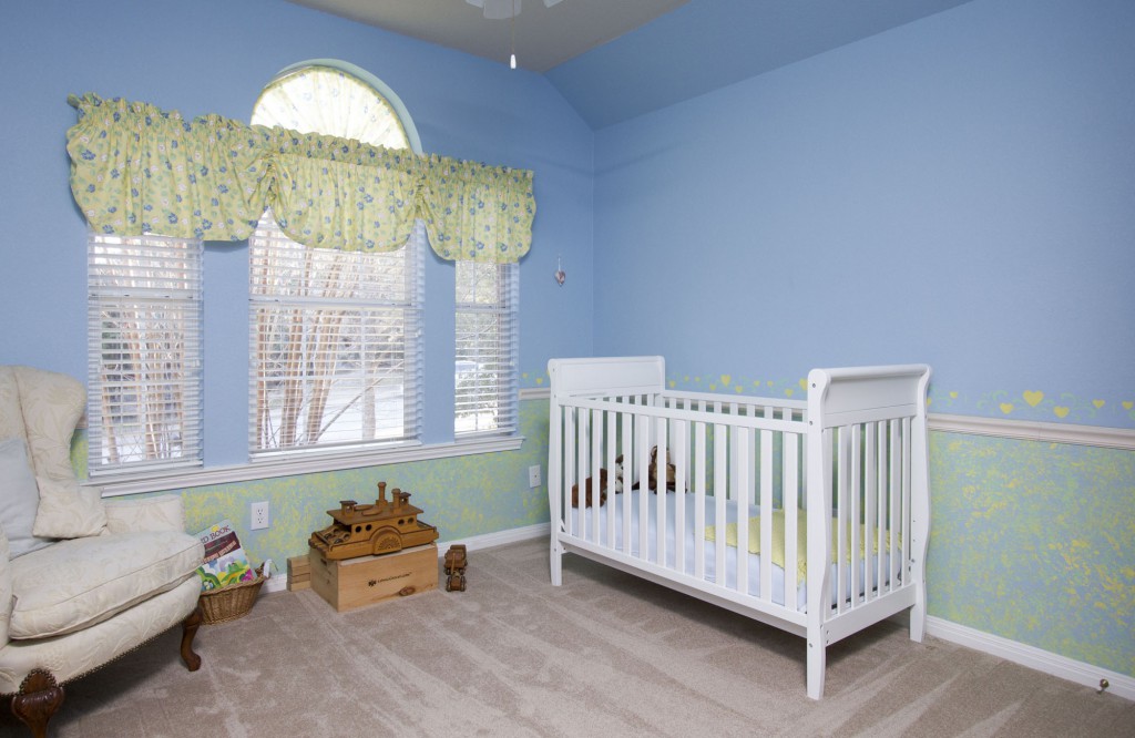View of childs bedroom with blue color and children's curtains.