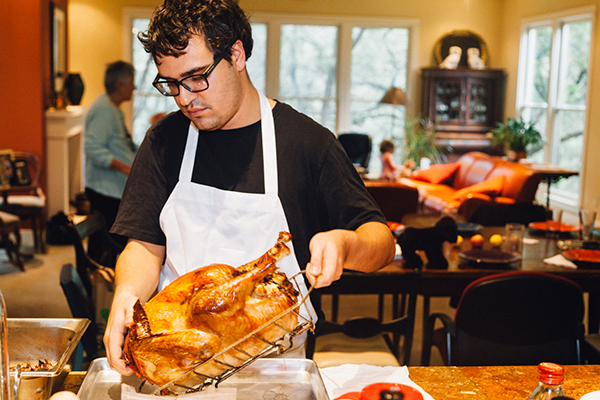 Matt Hejl, Realtor, at home preparing Thanksgiving dinner. Matt lifts turkey and get ready to slice.