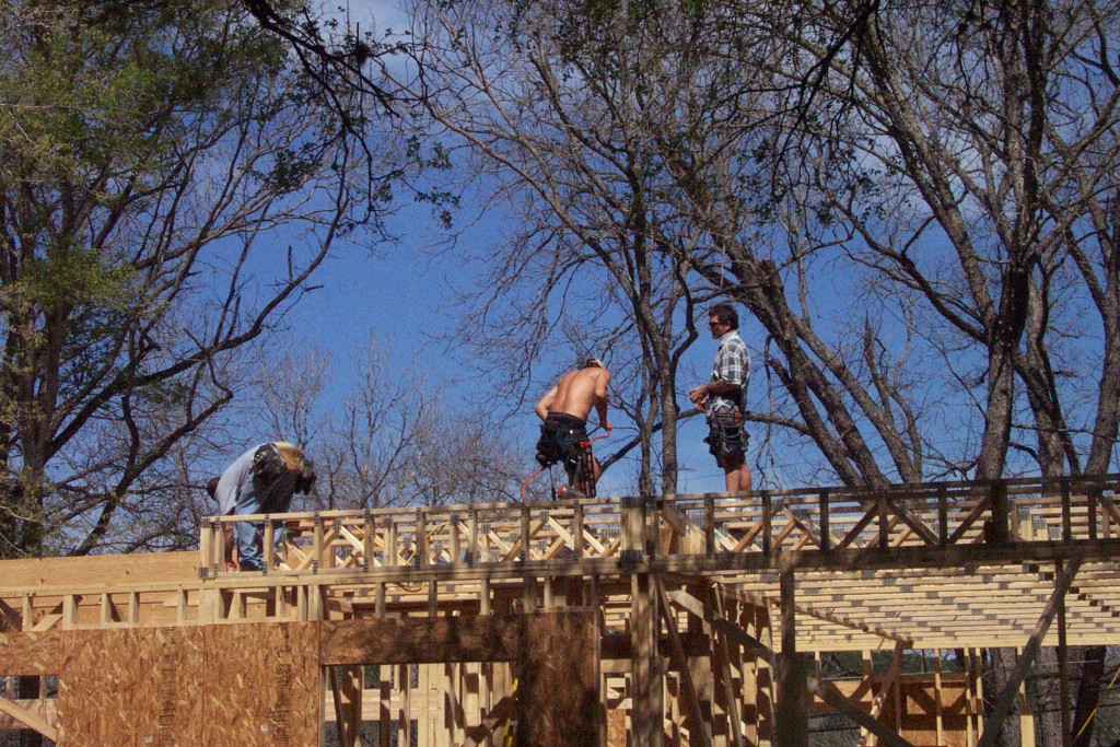 Framers on roof of house during construction. DIY craftsman being built.