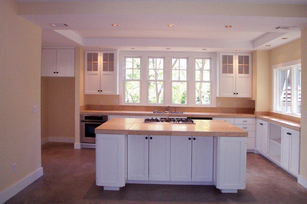 View of kitchen with marble counters, concrete floors, craftsman cabinet doors.