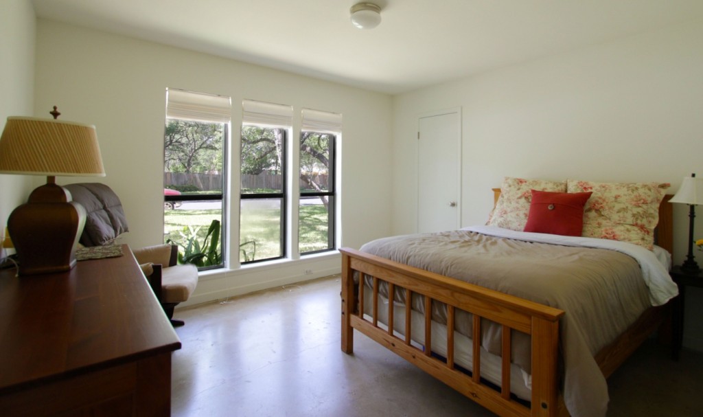 View of bedroom in ranch house remodel showing waxed concrete floor.