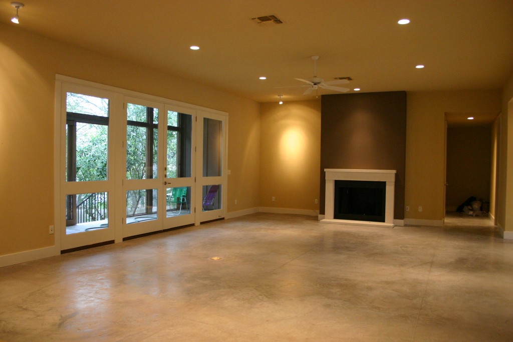 View of open plan living with focus on fireplace. Concrete floors.