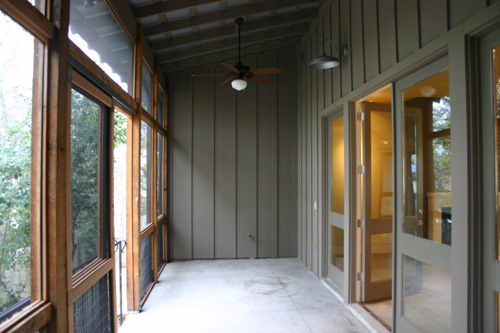 Screened porch has metal roof, farmhouse lighting, and board & batten siding.