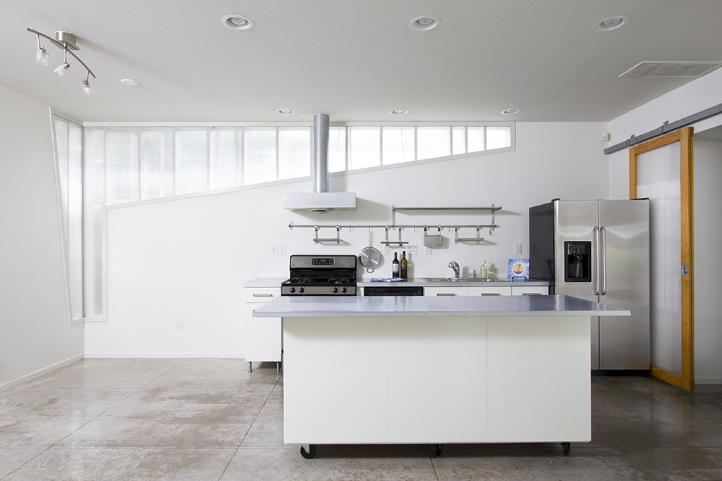 Austin home interiors - Modern condo kitchen with concrete floors, open plan.