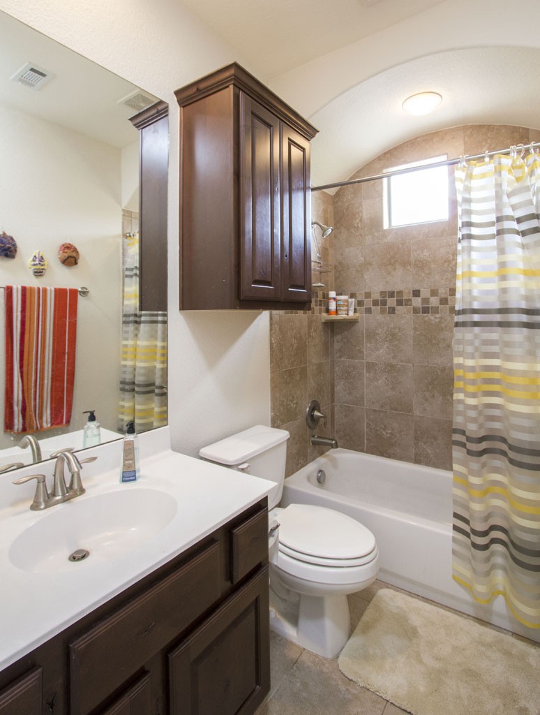 Hall bath upstairs has dark stained cabinetry, tile floors, cultured marble counter.