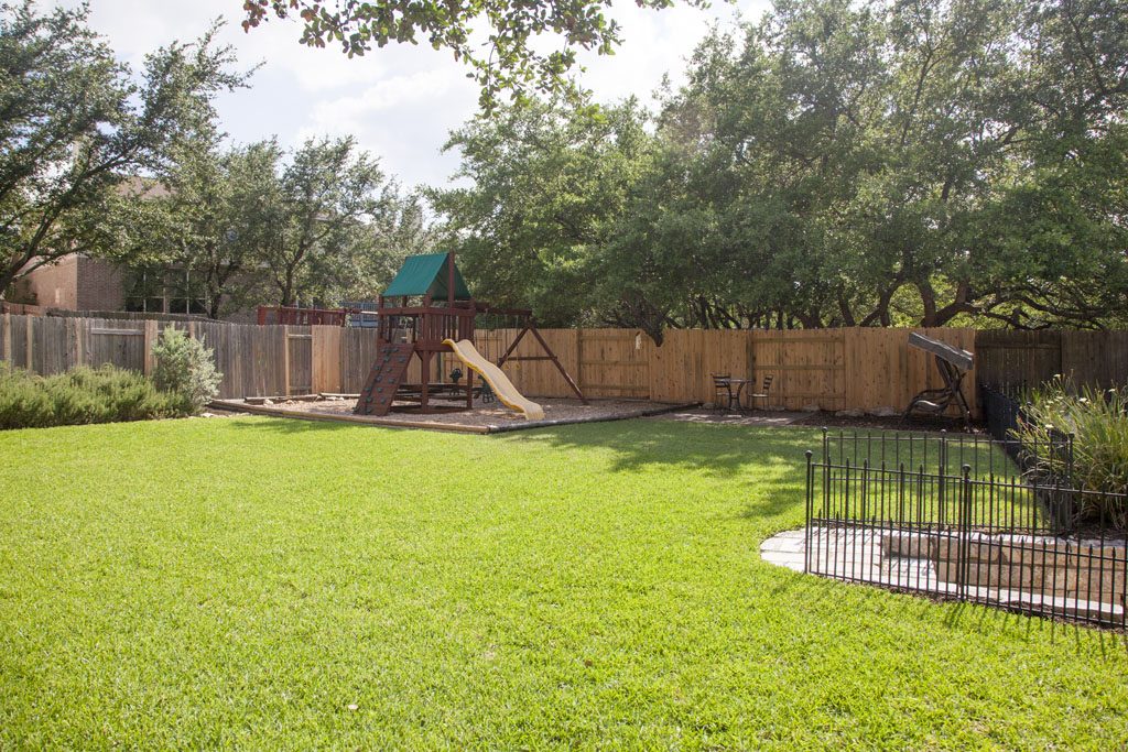 Upper level play area has trees, green grass, and landscaping. 