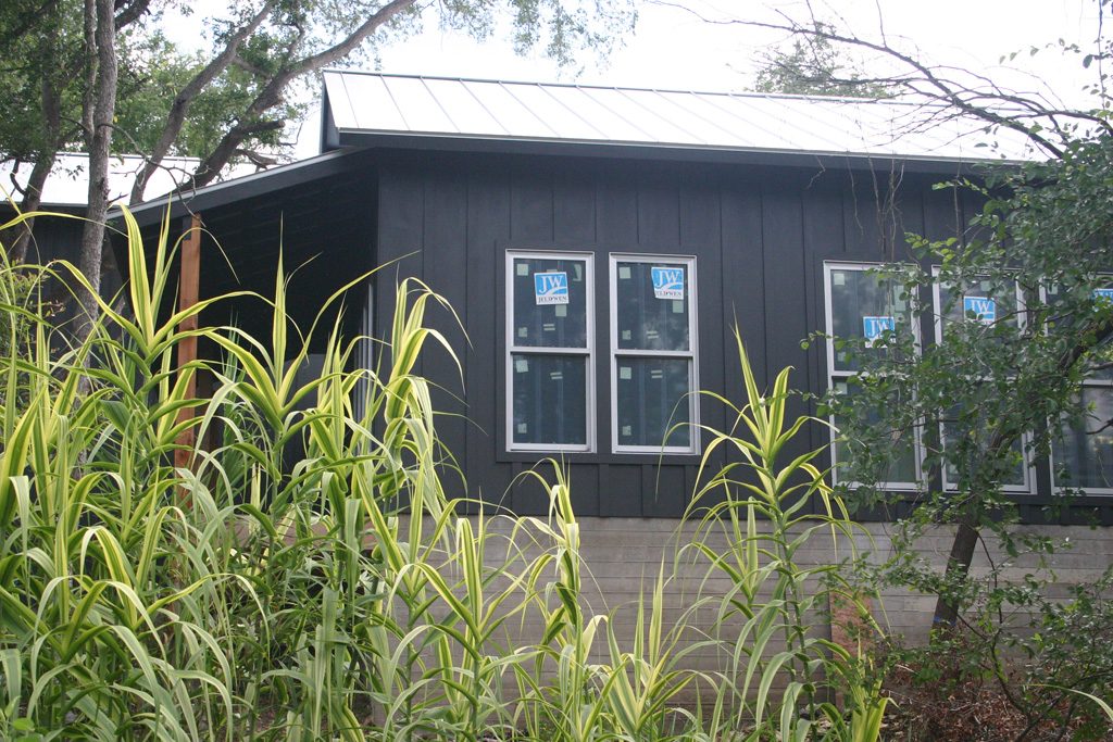 Side view of modern farmhouse board and batten siding, with metal roof, and dark gray paint. 