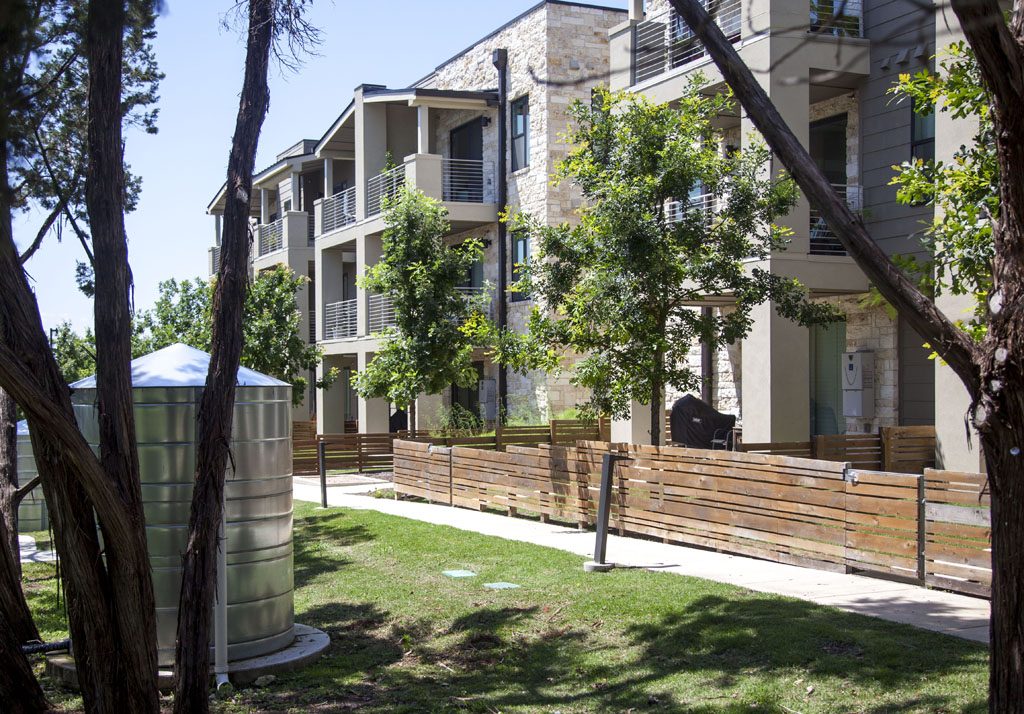 View of Denizen Condos water catchment tanks, trees, and privacy fencing.