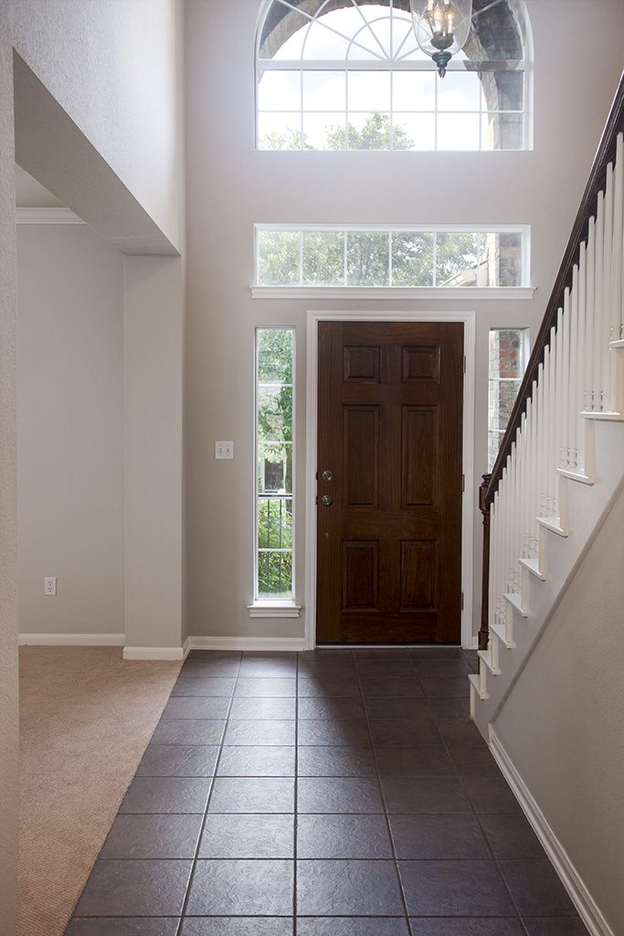 View of entry foyer with tile floor, high ceiling, and arched window over front door.