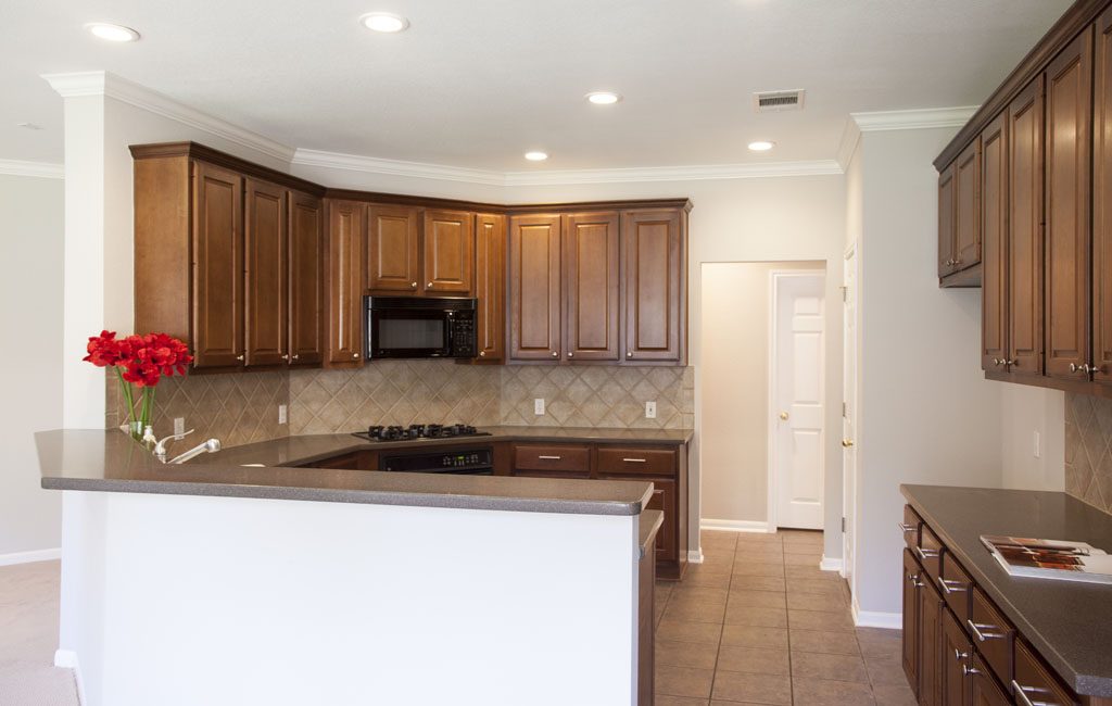 Spacious kitchen with tall cabinetry, gas cooktop, Corian counters, and tile floors.