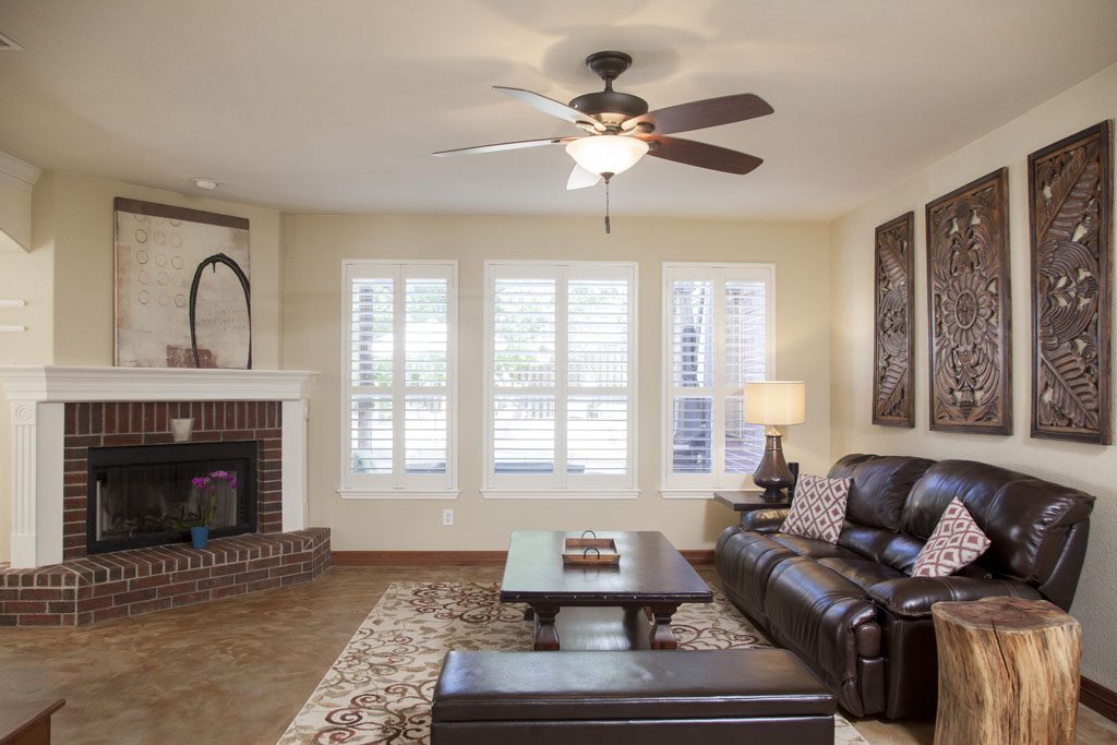 Central family room with white shutters and traditional brick fireplace.