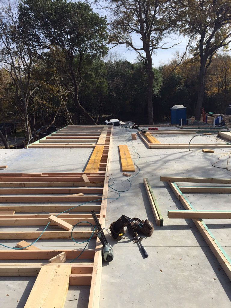 Modern farmhouse framing showing walls in first stage of framing laid out on concrete slab.