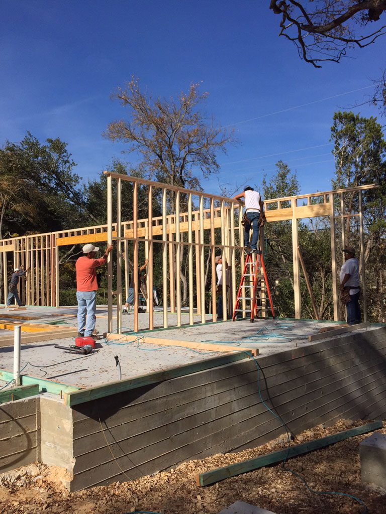 Carpenters joining walls during framing of modern farm house in Austin.