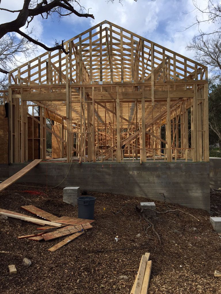 Modern farmhouse framing is in process with wall and roof trusses in place.