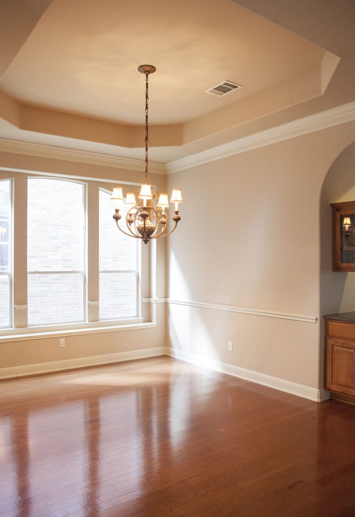 View of formal dining with chandelier and coffered ceiling.