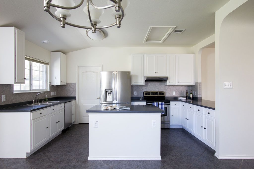 Large kitchen with stainless appliances, tile floors, corian counters.